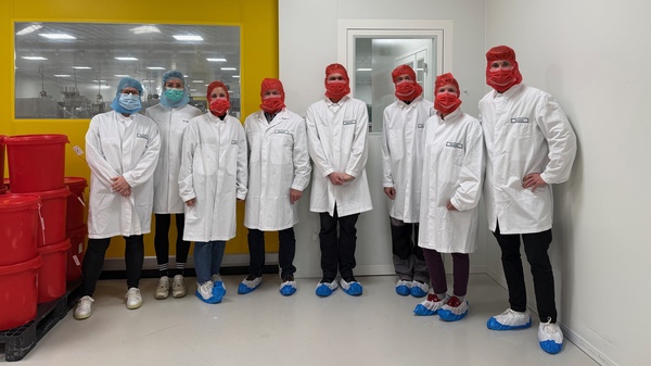 Die Gruppe aus den KJF Werkstätten steht im Produktionsbereich der Firma Vital Products. Alle tragen aus Hygienegründen Schutzkleidung.