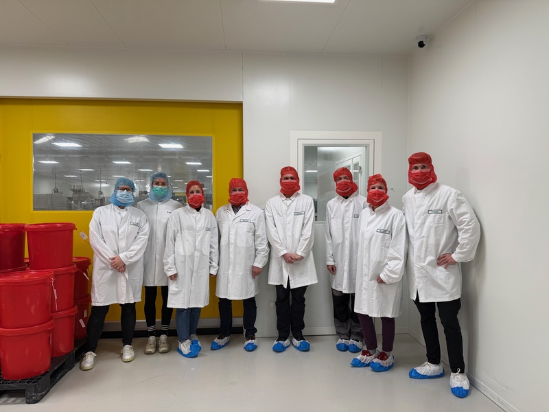 Die Gruppe aus den KJF Werkstätten steht im Produktionsbereich der Firma Vital Products. Alle tragen aus Hygienegründen Schutzkleidung.