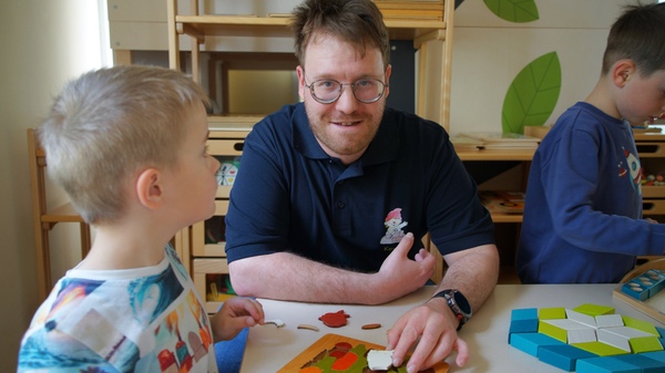 Kevin Blay spielt mit einem Kind im Kindergarten.