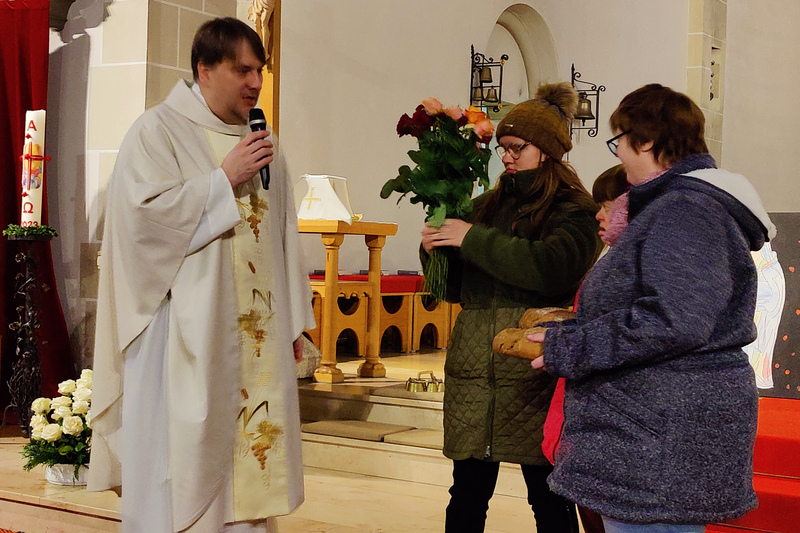 Während des Gottesdienstes zeigen Mitarbeiterinnen der Werkstätte einen Rosenstrauß und Brot