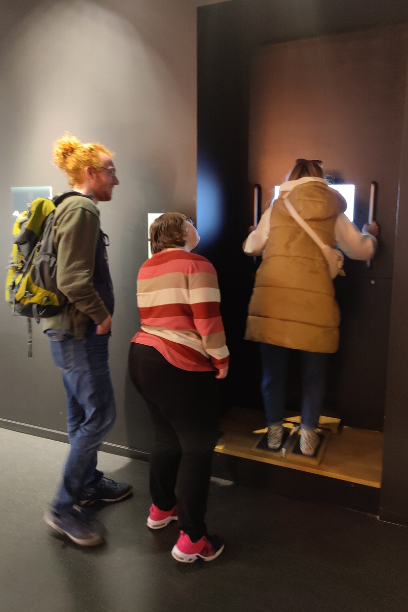 Drei Personen betrachten Exponat im Museum