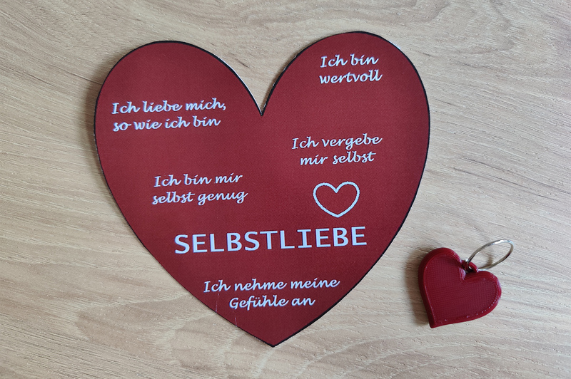 Ein Papierherz mit ein paar Tipps zur Selbstliebe und der Schlüsselanhänger in Herzform.