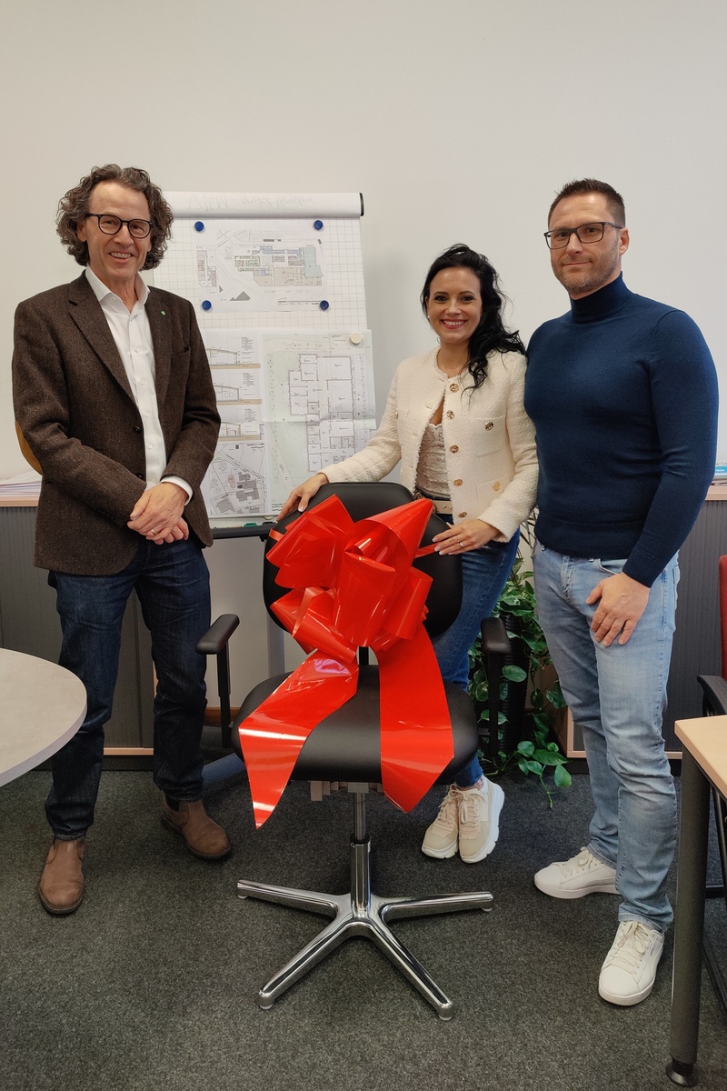 Firma Ottmar Heckl überreicht Bürostuhl mit roter Schleife.