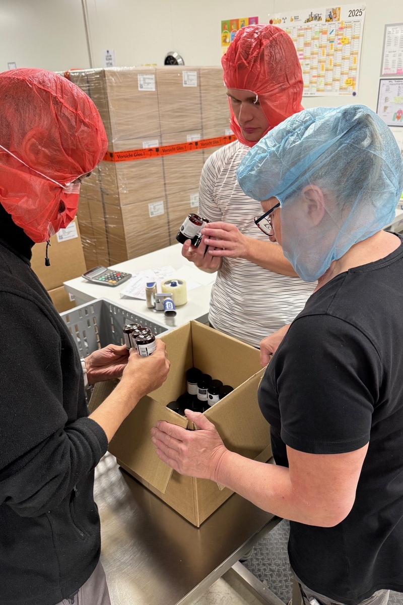 Die Mitarbeiter der KJF Werkstätten arbeiten verpacken Nahrungsergänzungsmittel. Sie tragen Schutzkleidung.